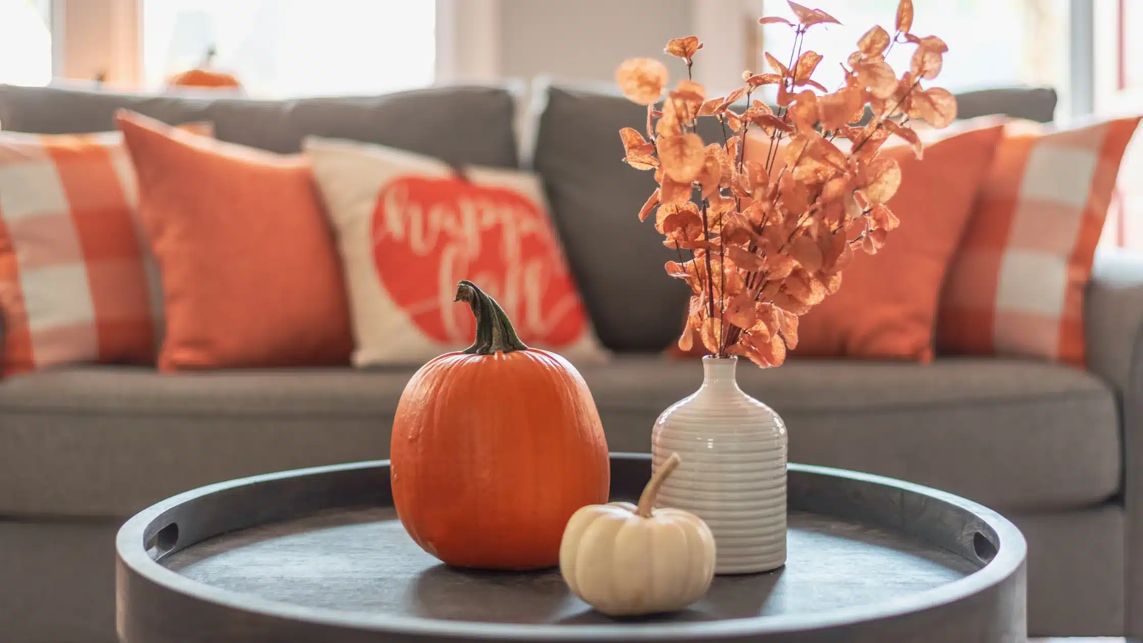 Fall Home Maintenance Tips | Pumpkins and fall floral arrangement sit on a coffee table
