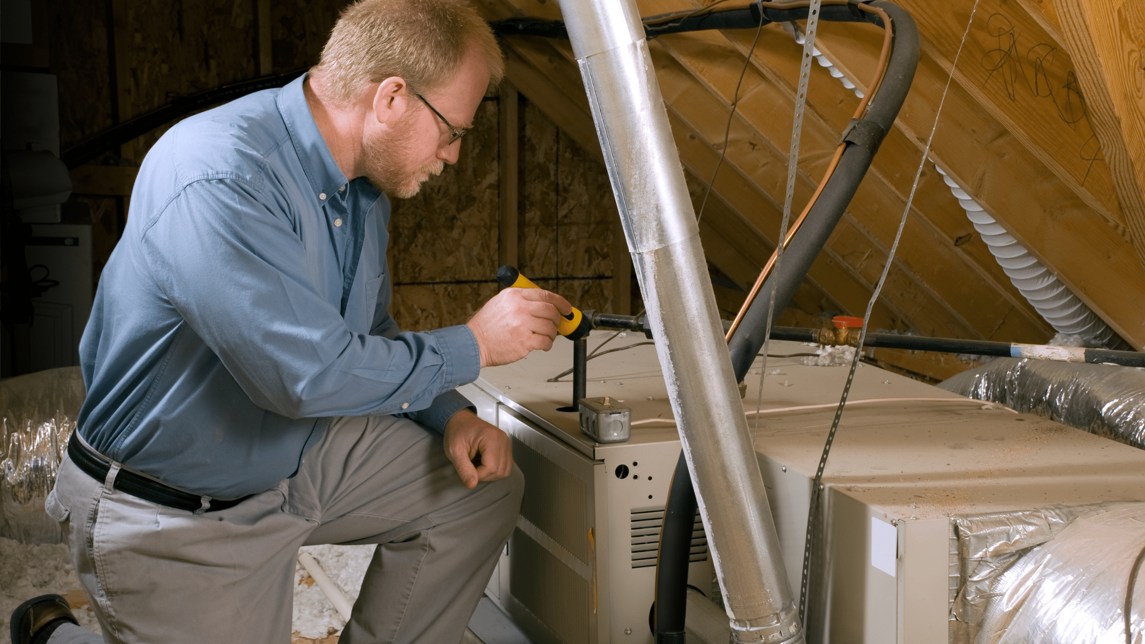 HVAC Technician inspecting furnace in attic | HVAC Maintenance Plan